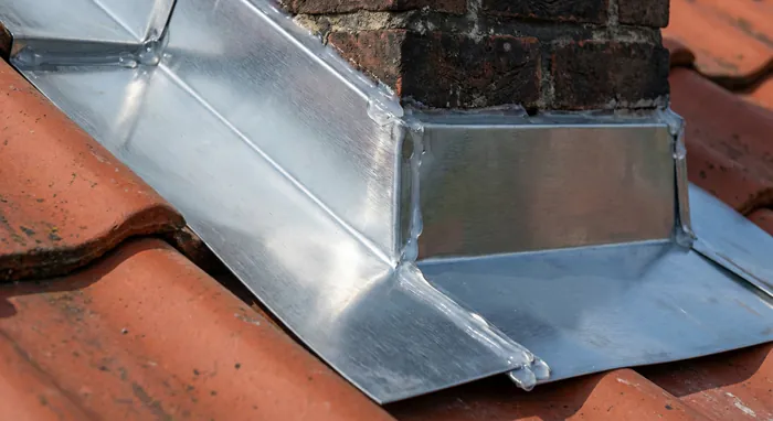 Tarif pose abergement de cheminée : Prix et Devis 2026 - Prix abergement cheminée 2026 : Le Guide Ultime - Fuite de toit ? Tarif pose abergement de cheminée Zoom sur un abergement de cheminée en zinc neuf et étanche.